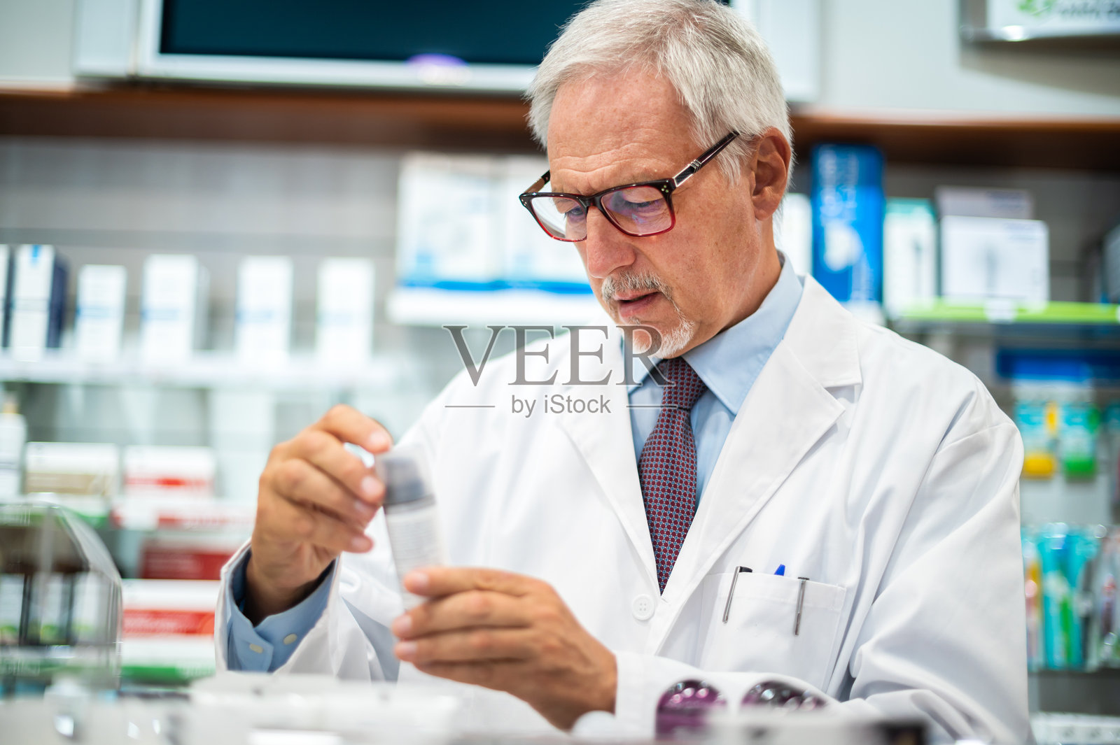 资深药剂师在药房仔细检查药瓶照片摄影图片