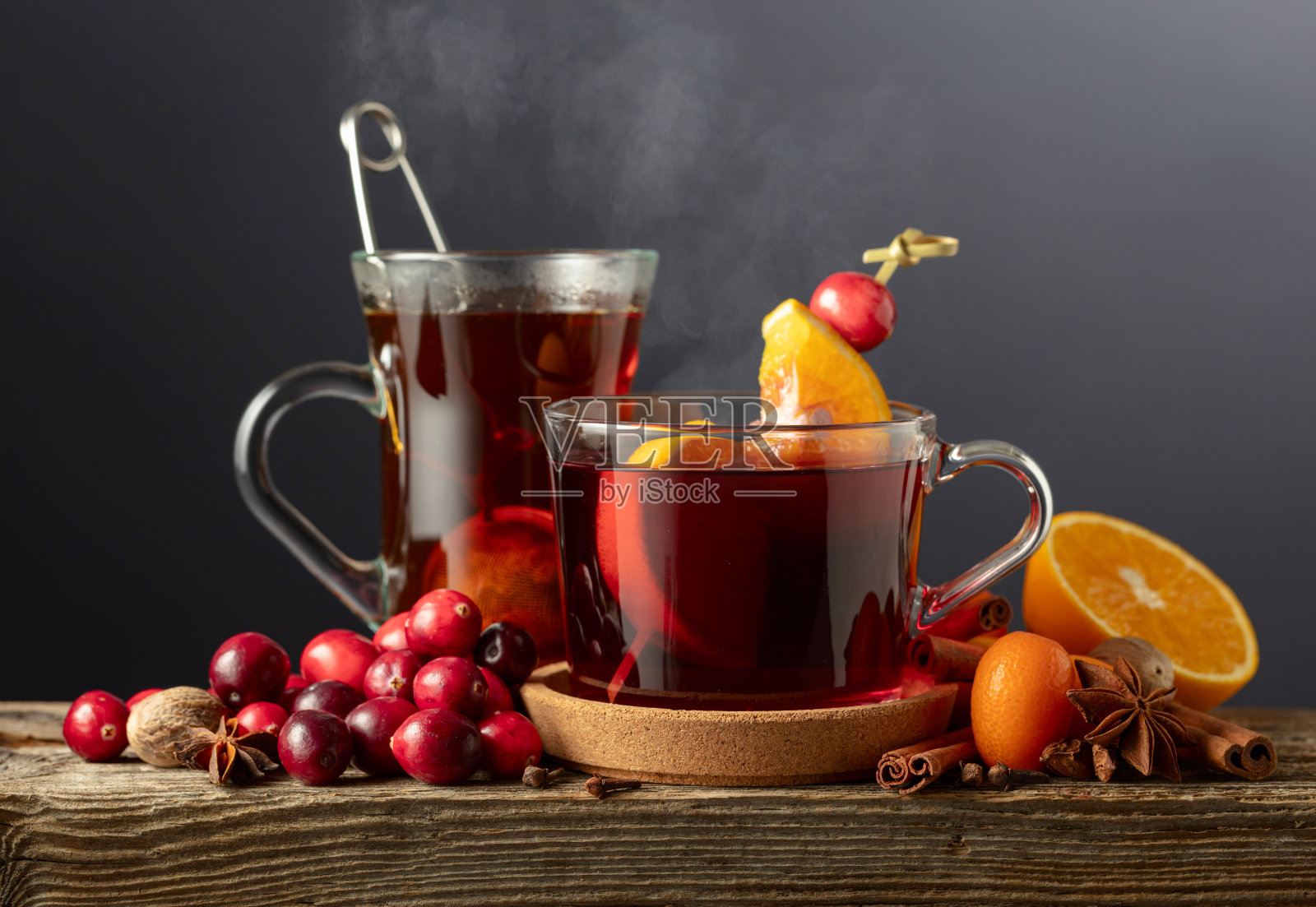 冬季饮品，配有香料、蔓越莓和柑橘类水果，背景为深色。照片摄影图片