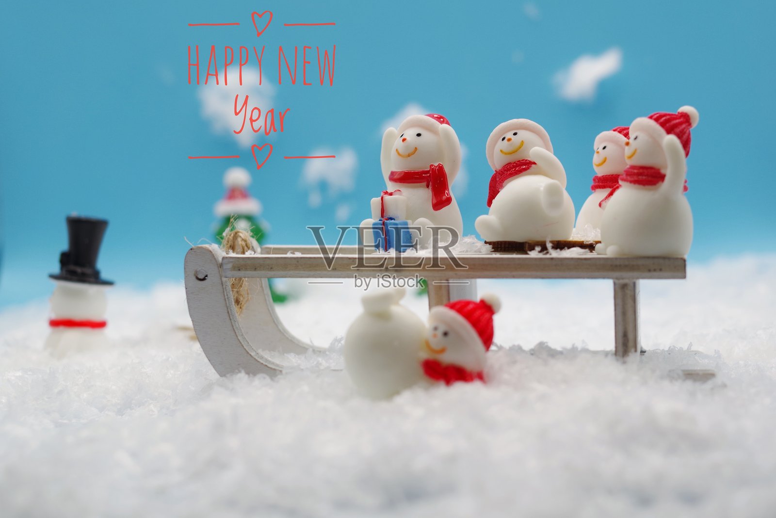 2025年新年快乐，圣诞快乐。许多小雪人在雪橇上坐着。贺卡。四周都是雪。冬季概念。雪景背景。照片摄影图片