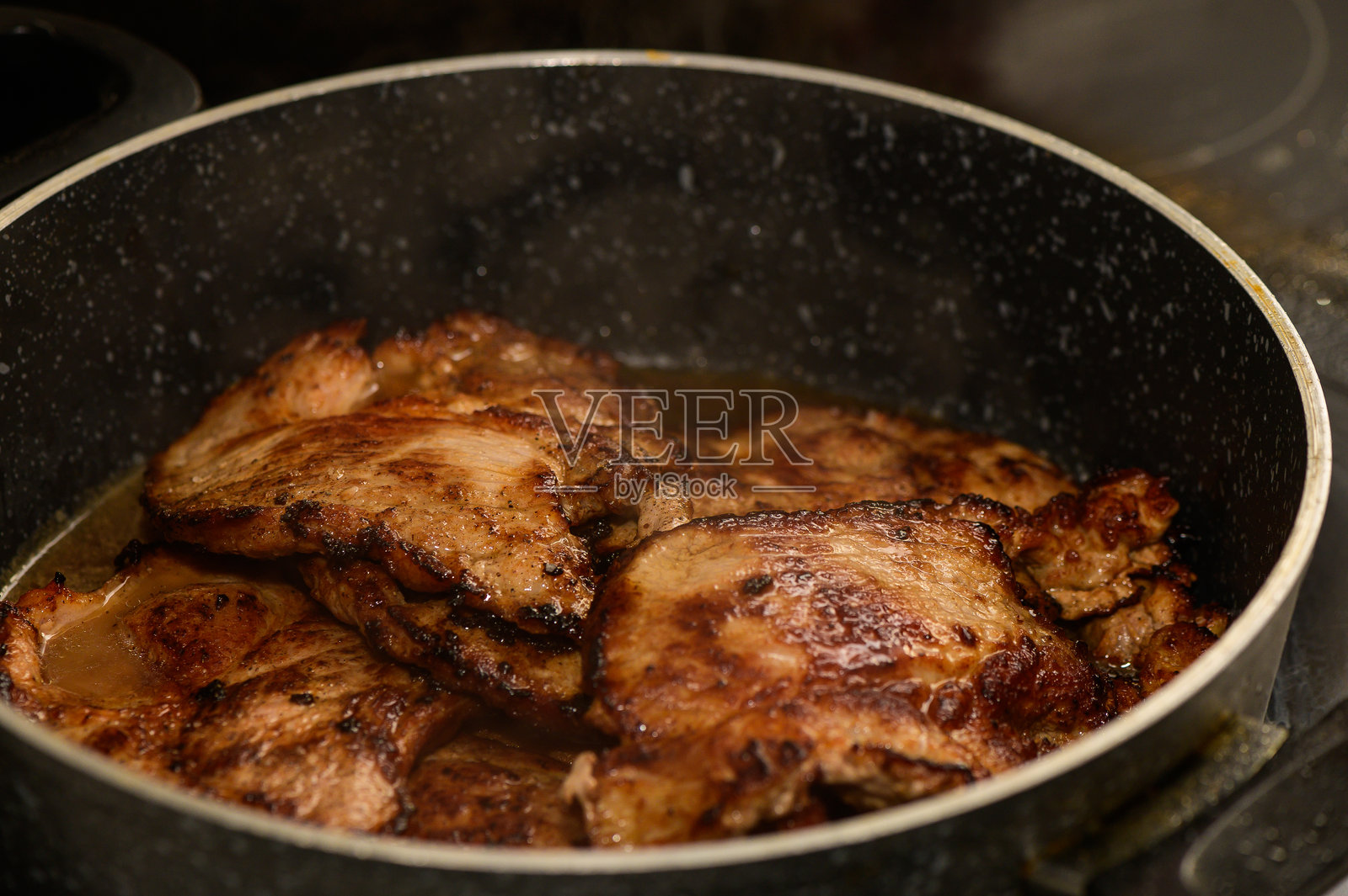 美味的肉在锅中滋滋作响，捕捉到温馨厨房环境中家常菜的精髓照片摄影图片