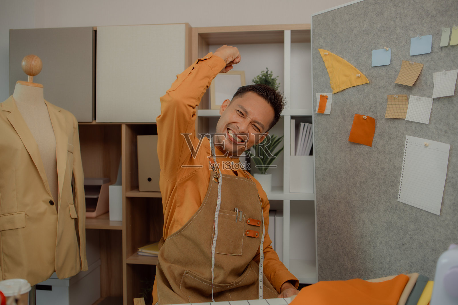 一位时装设计师在他的工作室中展示各种姿势，一位裁缝在时尚房间中摆姿势拍照，表达不同的情感，时尚、服装、流行、纺织品。照片摄影图片