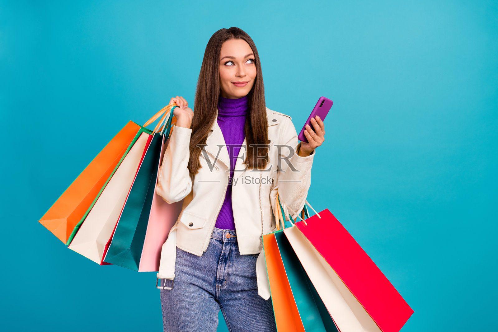 调皮的女士使用设备查看空旷空间，考虑决定在蓝色背景下的精品购物中心。照片摄影图片