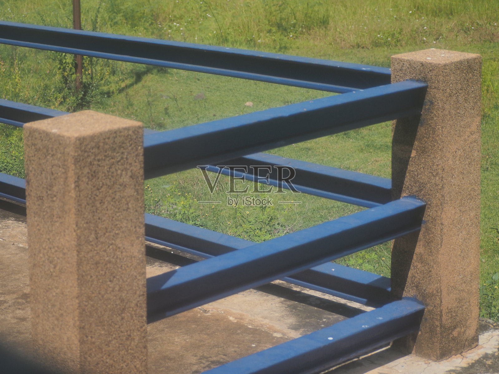 蓝色、黑色和棕色的围栏和柱子，绿色的草地照片摄影图片
