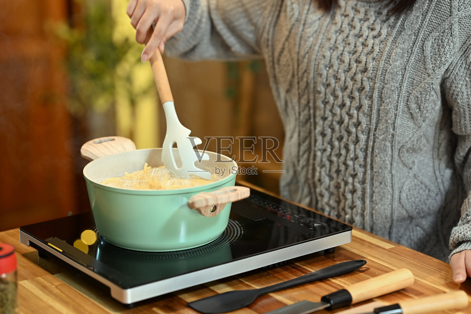 女人在绿色锅中搅拌意大利面，假期期间准备餐点的特写镜头照片摄影图片