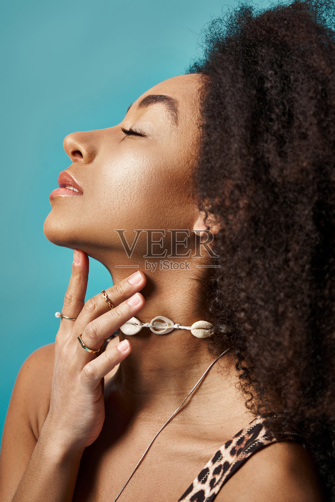 年轻女性在创意环境中展示独特的珠宝，背景为生动的绿松石色。照片摄影图片