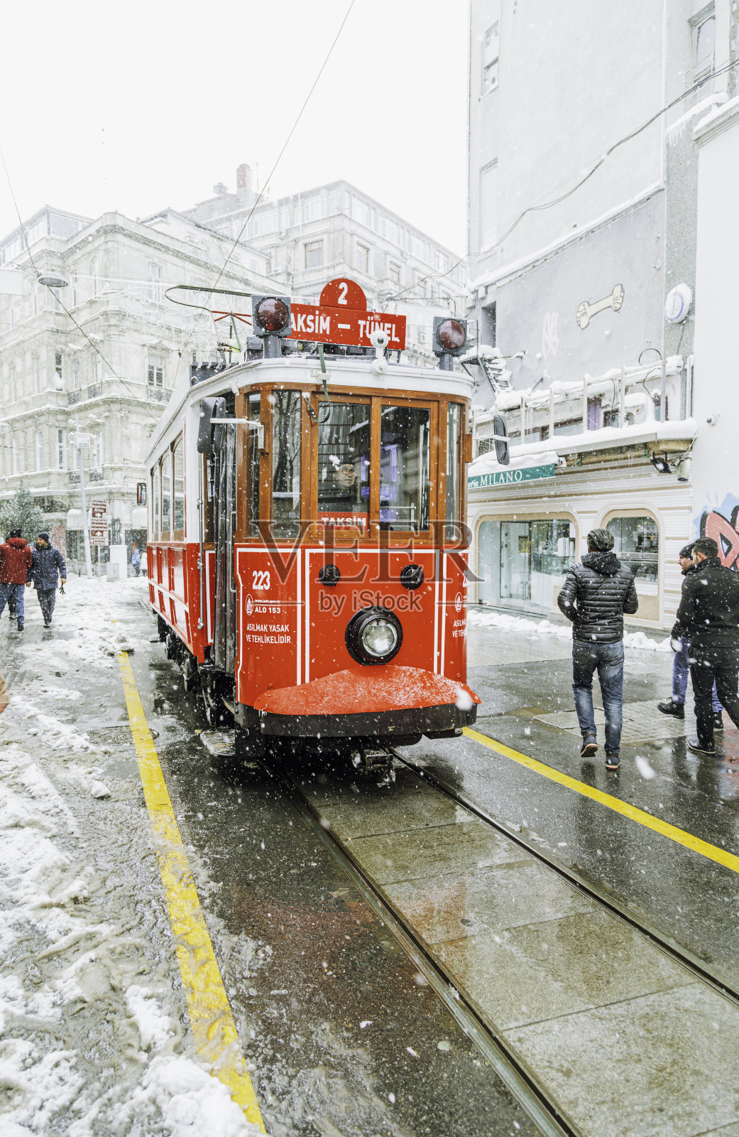 历史悠久的红色电车在土耳其伊斯坦布尔贝尤鲁的独立大街上，雪景中的冬季场景照片摄影图片
