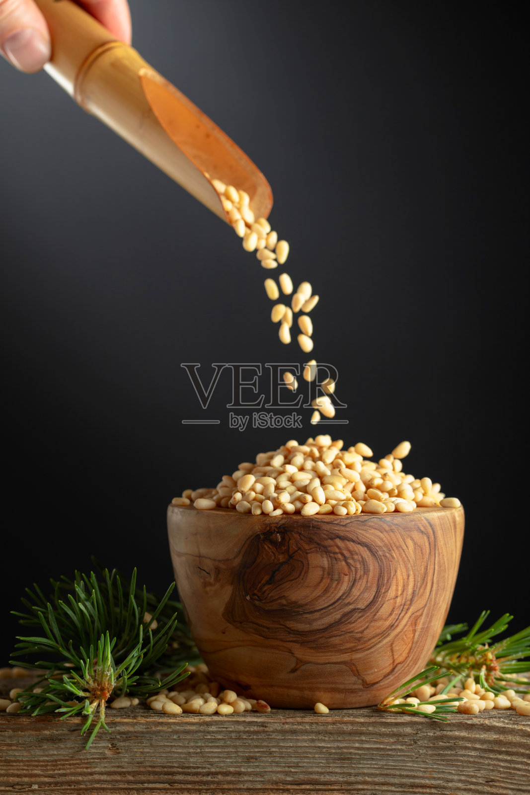 松子被倒入一个木碗中。照片摄影图片