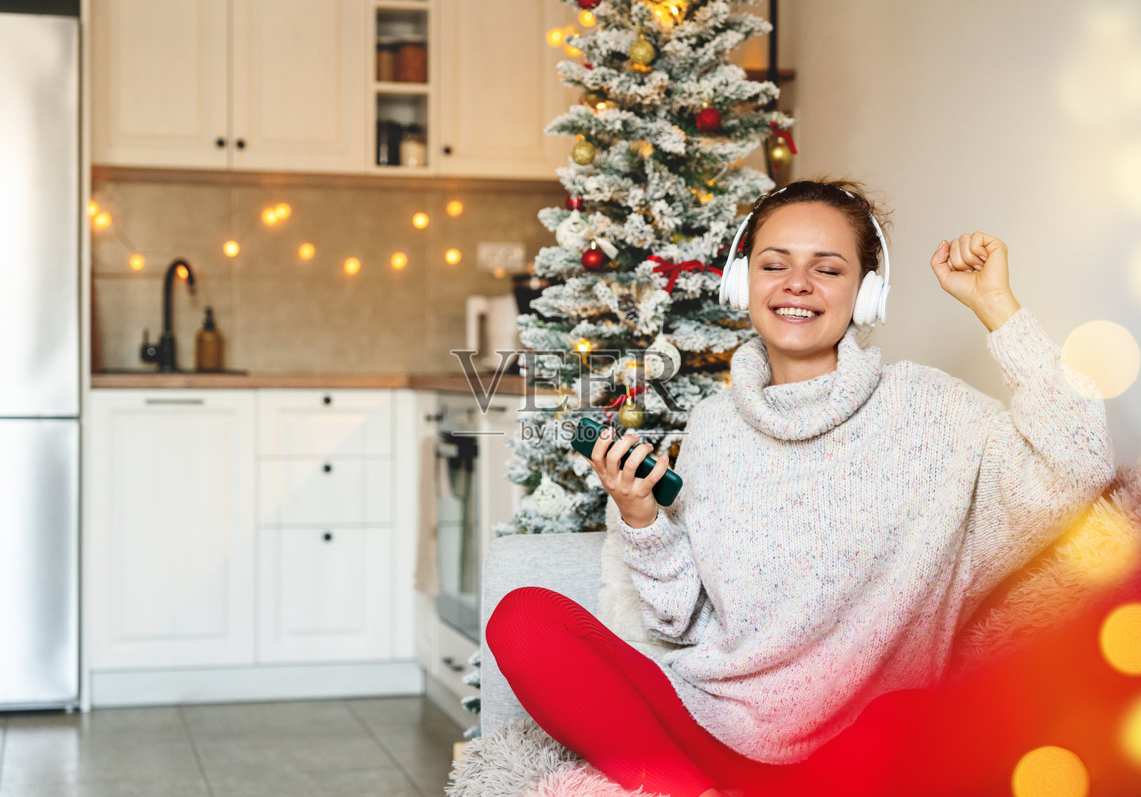 女人在圣诞假期时在家中享受音乐，佩戴无线耳机。照片摄影图片