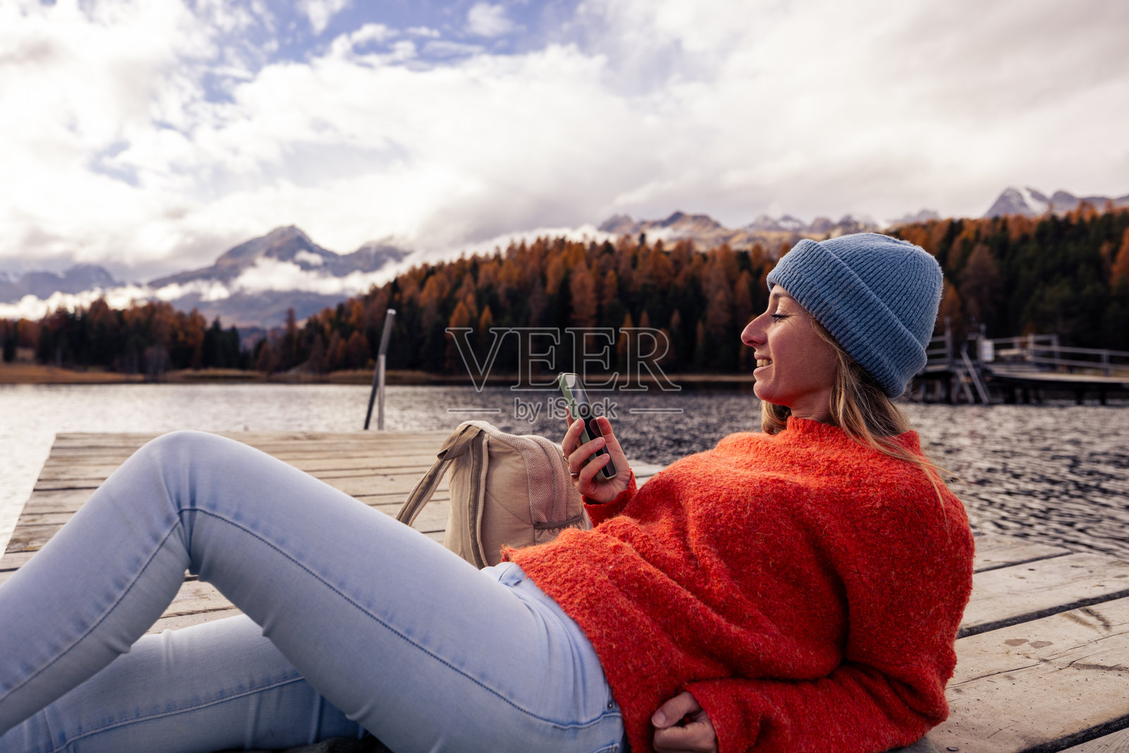女人在湖边的码头上放松，使用她的智能手机照片摄影图片