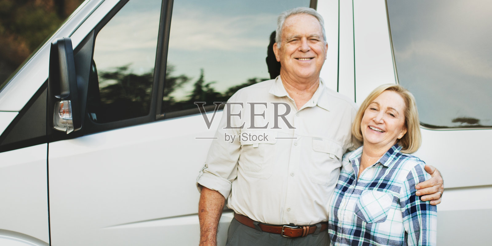 快乐的老年夫妇站在一辆面包车旁。照片摄影图片