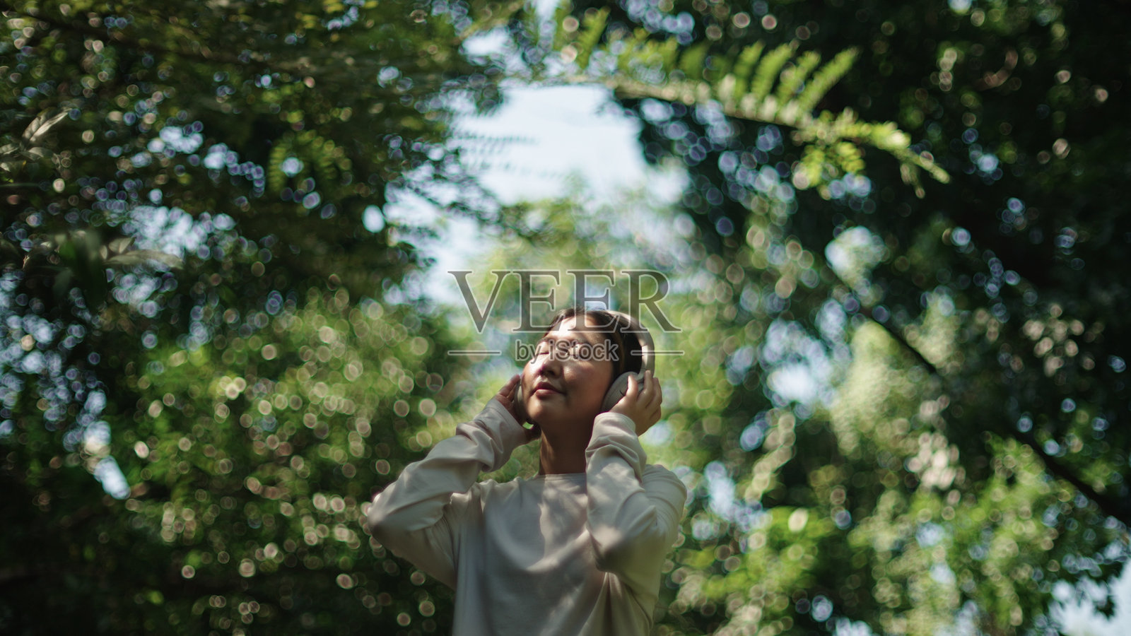 女人在大自然中放松时佩戴耳机。照片摄影图片