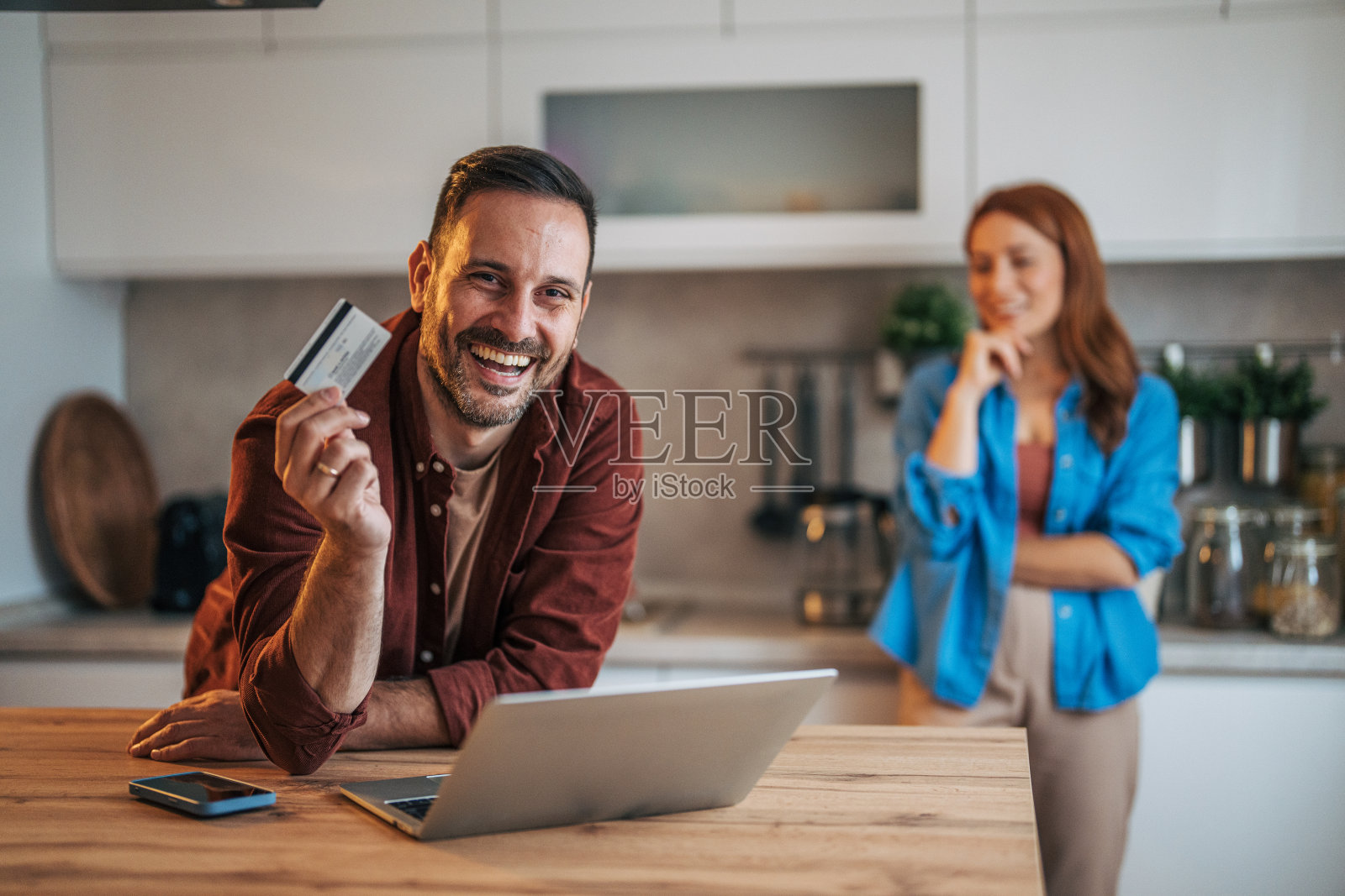 一对快乐的夫妻站在厨房里。照片摄影图片