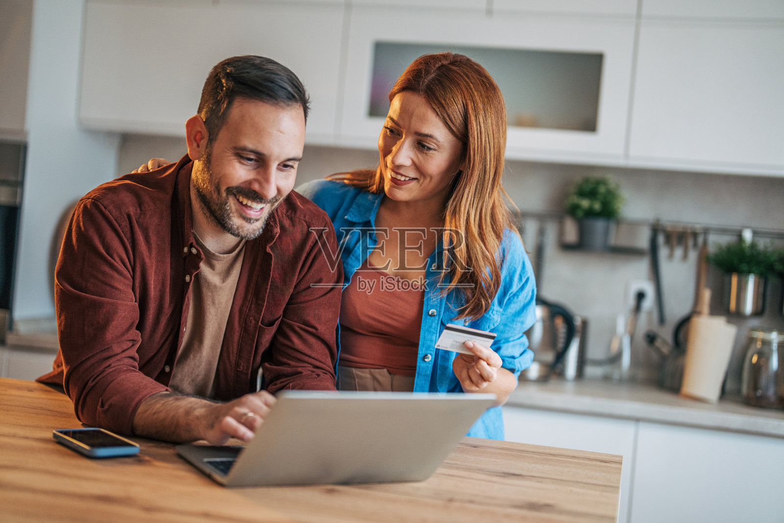 一对快乐的夫妻站在厨房里。照片摄影图片