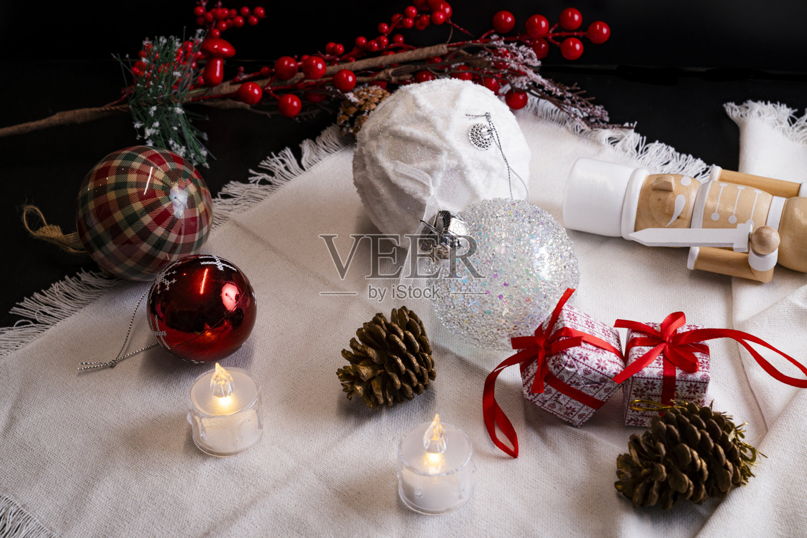 白色和红色的圣诞装饰桌，包括胡桃夹子、雪白的圣诞球、蜡烛、红色浆果和礼物照片摄影图片