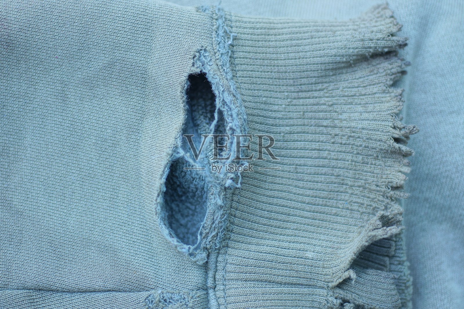 破旧衣物的撕裂布料纹理，带有一个洞照片摄影图片