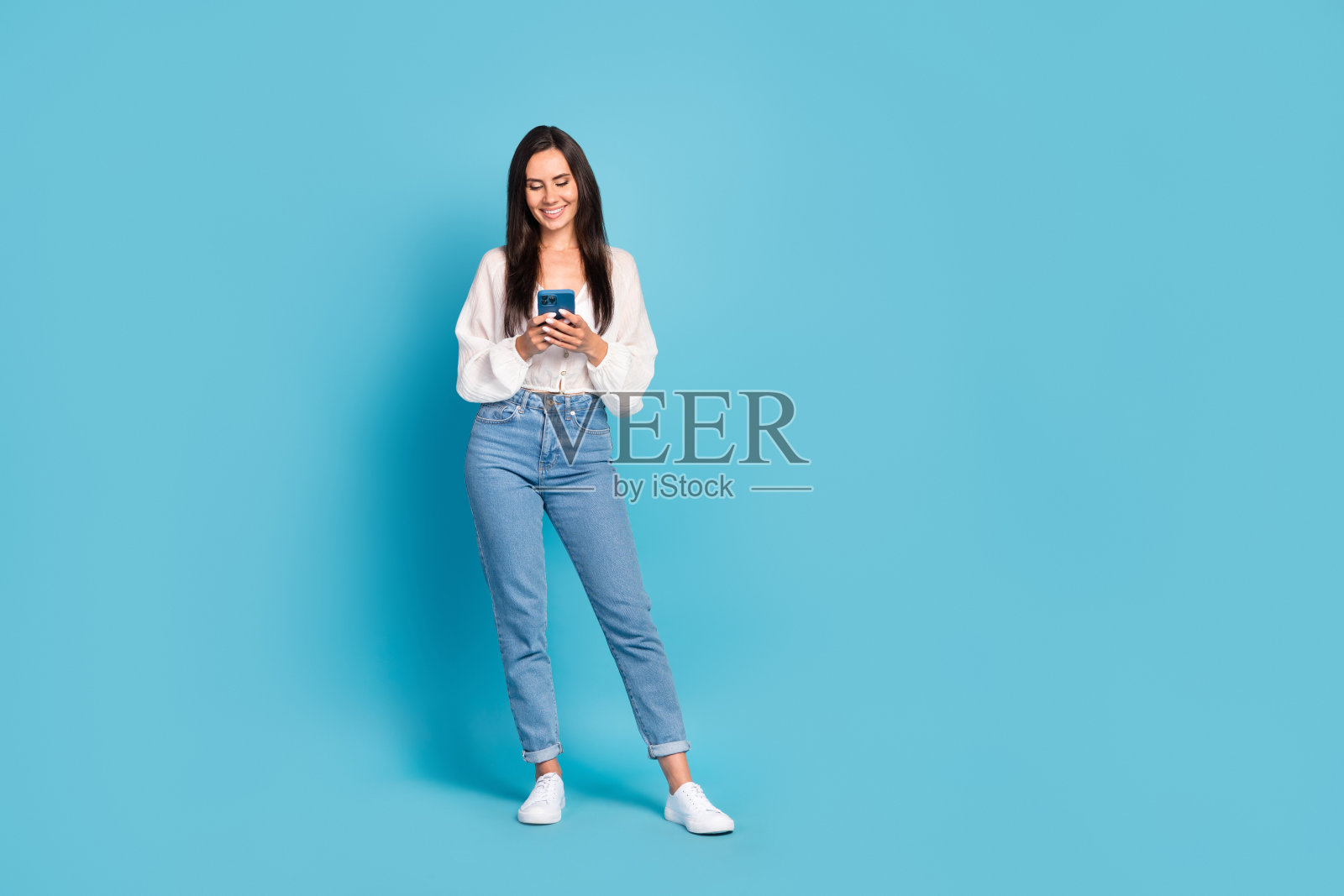 全身肖像，迷人积极的女孩手持电话，空白空间，背景为蓝色照片摄影图片