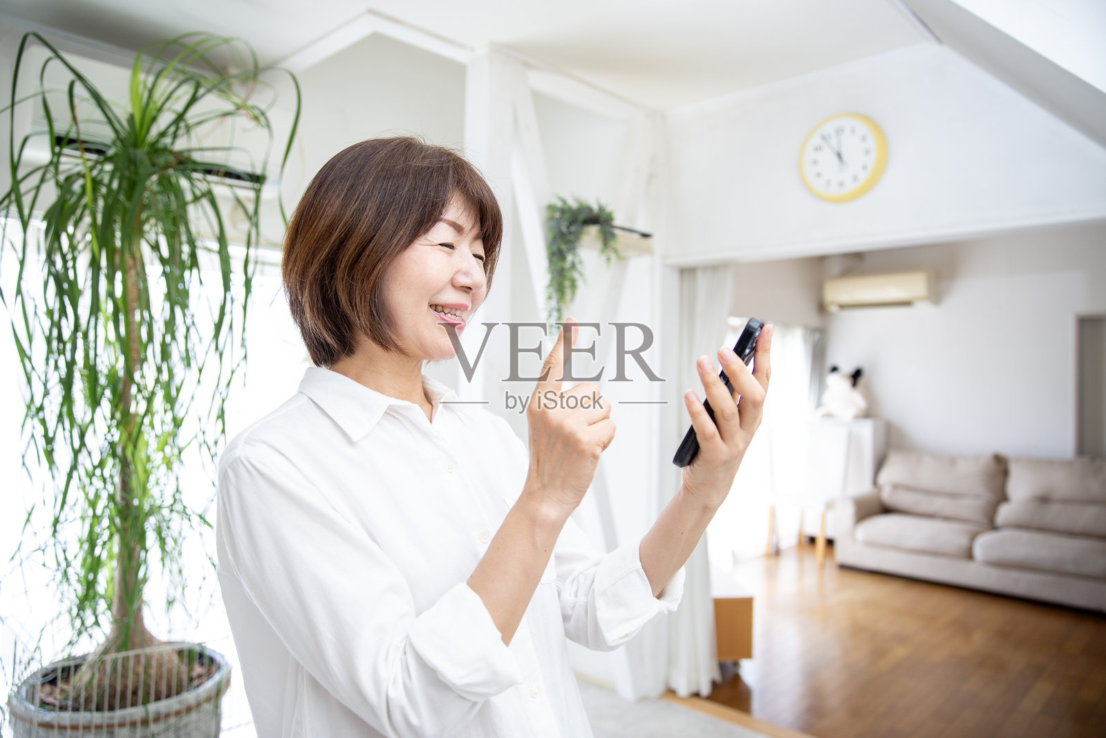 一位担忧的中年日本女性在家中的客厅使用智能手机照片摄影图片