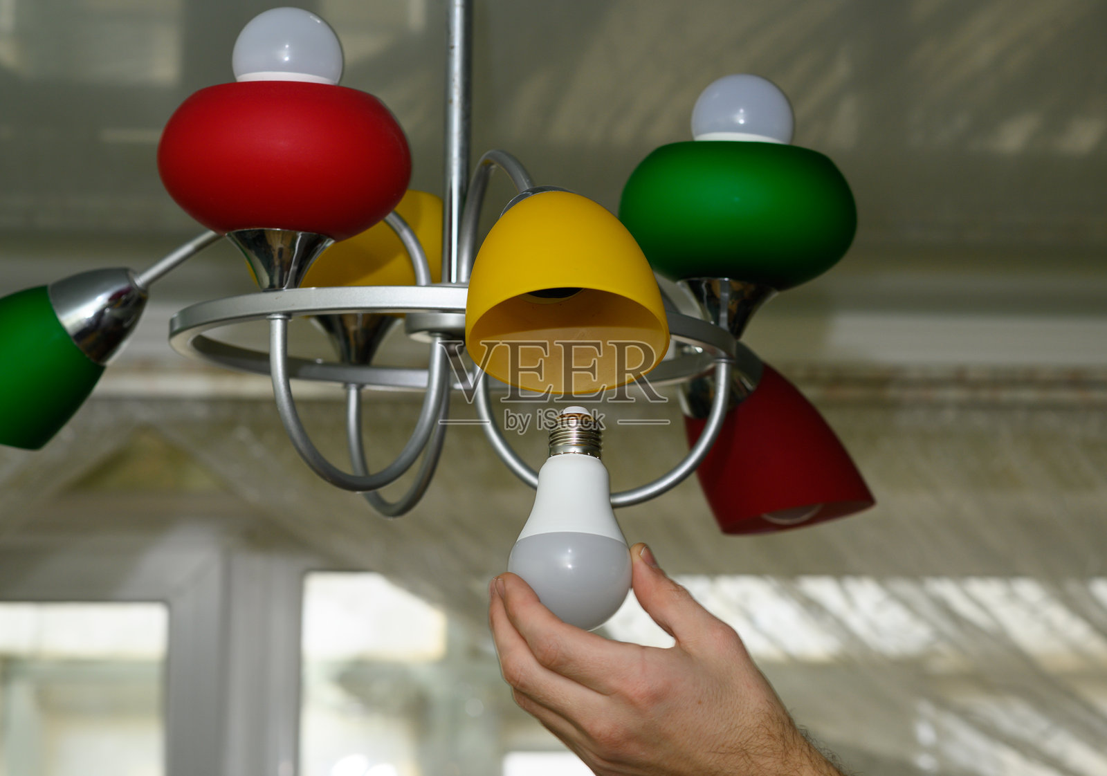 女性手正在灯具中安装LED灯泡。照片摄影图片