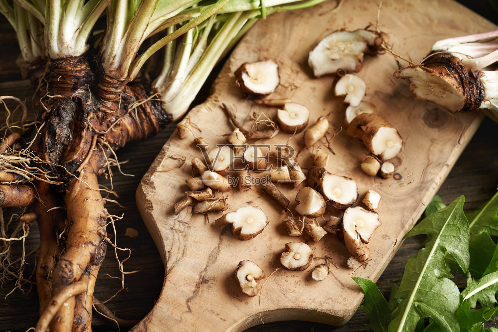 切碎新鲜的蒲公英根 - 草药酊剂的准备照片摄影图片