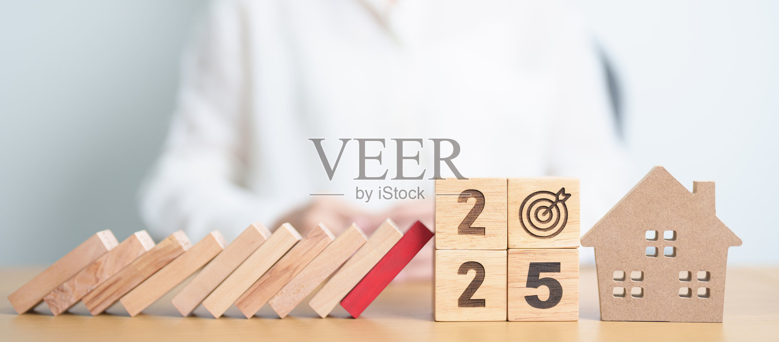 2025年，木块掉落到家庭模型和商业图标上。房地产抵押贷款、再融资、房屋贷款和债务、利率、保险、金融财产和经济衰退。照片摄影图片