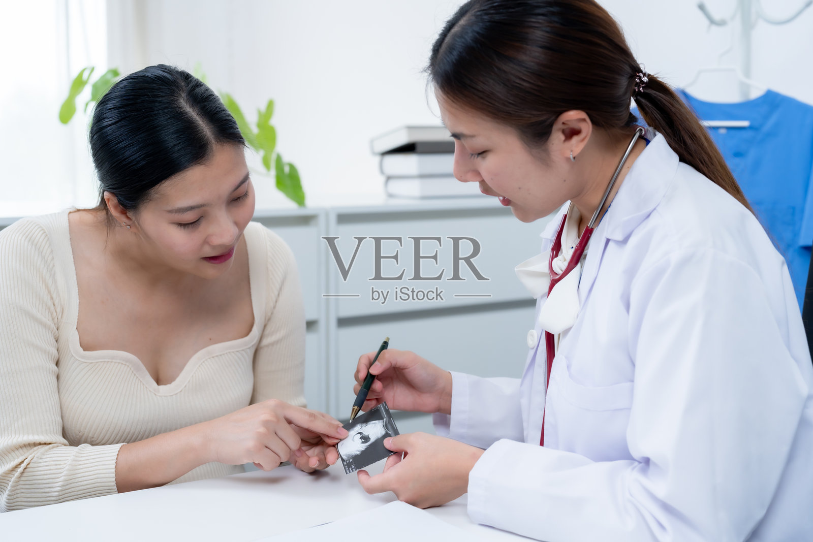 女性医生在产前咨询中向孕妇解释超声图像，进行健康讨论。亲密的医疗环境支持、理解和关怀即将成为母亲的女性。照片摄影图片