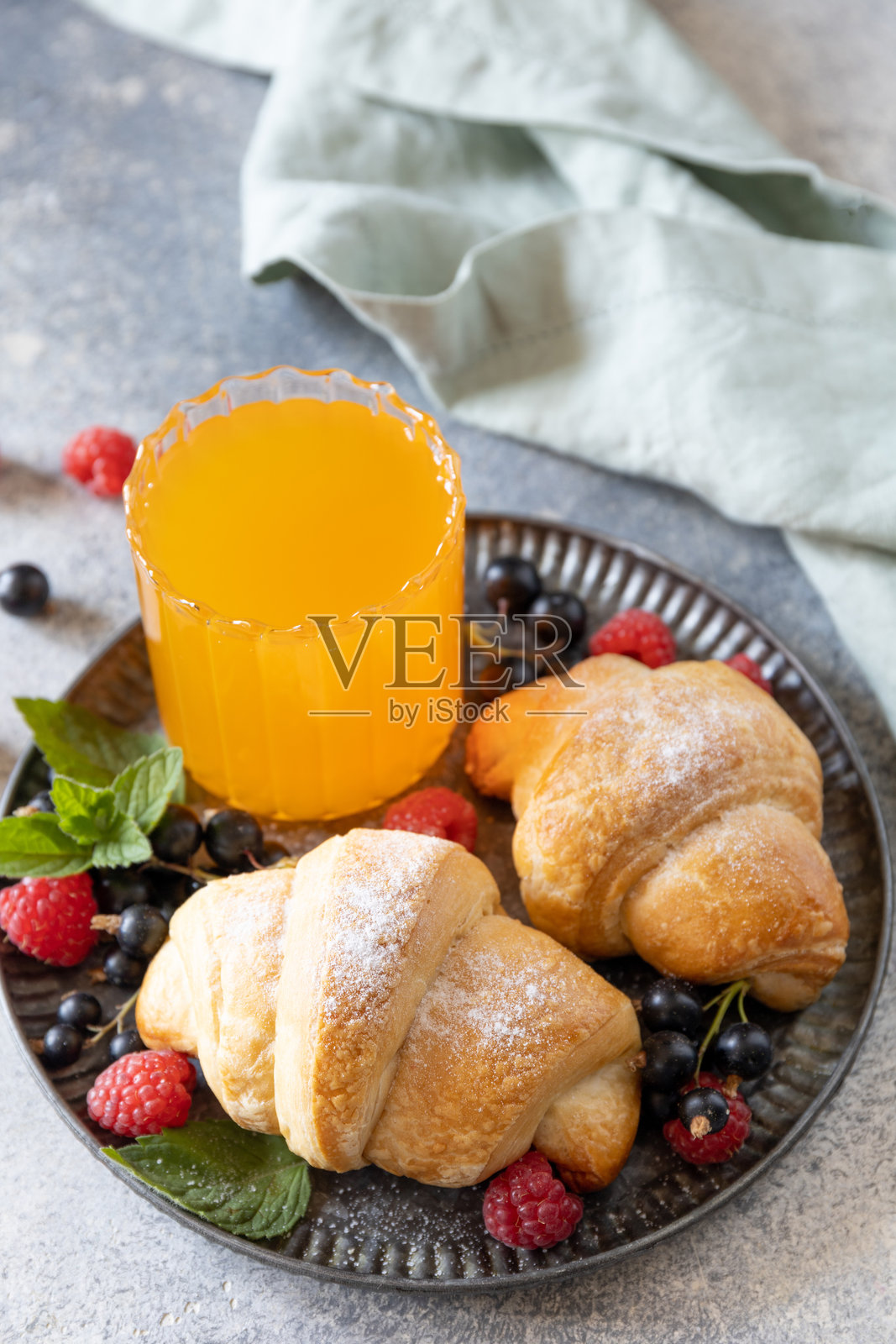 美味的新鲜烤可颂和橙汁，背景为灰色石材，早餐概念。照片摄影图片