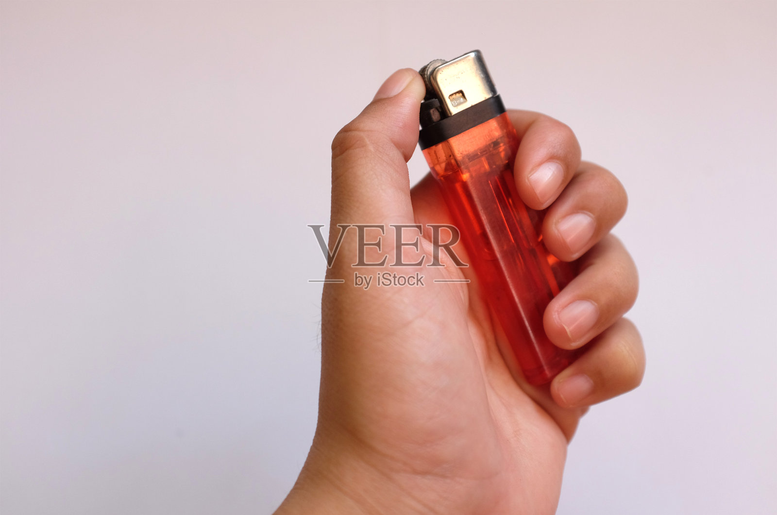 白色背景下，手握打火机的人手部特写照片摄影图片