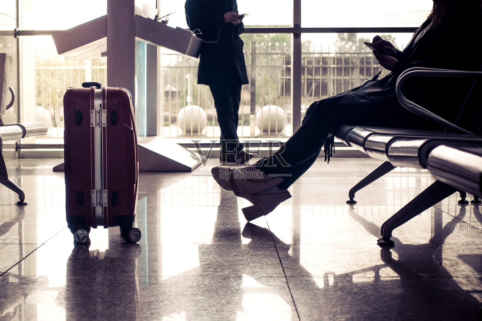 机场窗边坐着的女性下半身与行李箱照片摄影图片