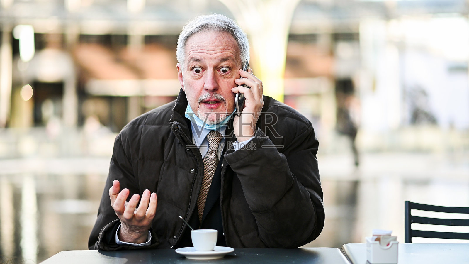 震惊的商人在户外咖啡馆接到令人难以置信的电话消息照片摄影图片