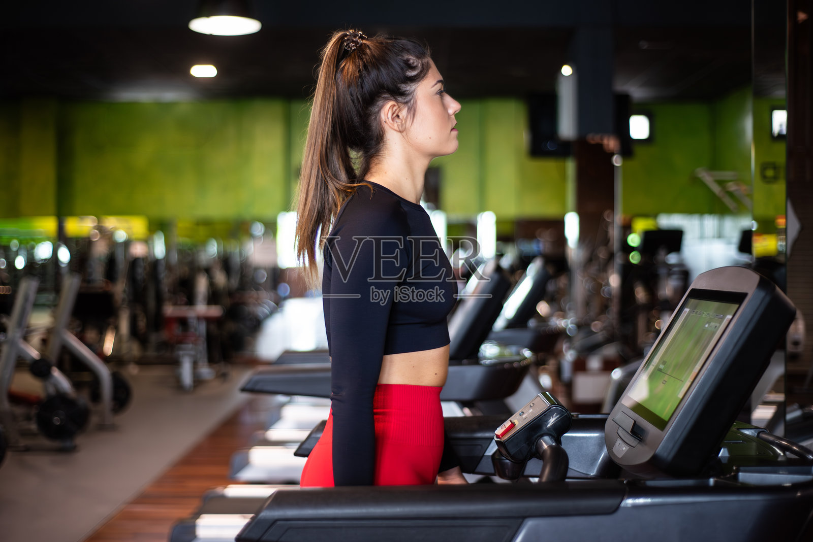 年轻女性在健身房的跑步机上锻炼和训练。健康的生活方式和积极的人们。照片摄影图片
