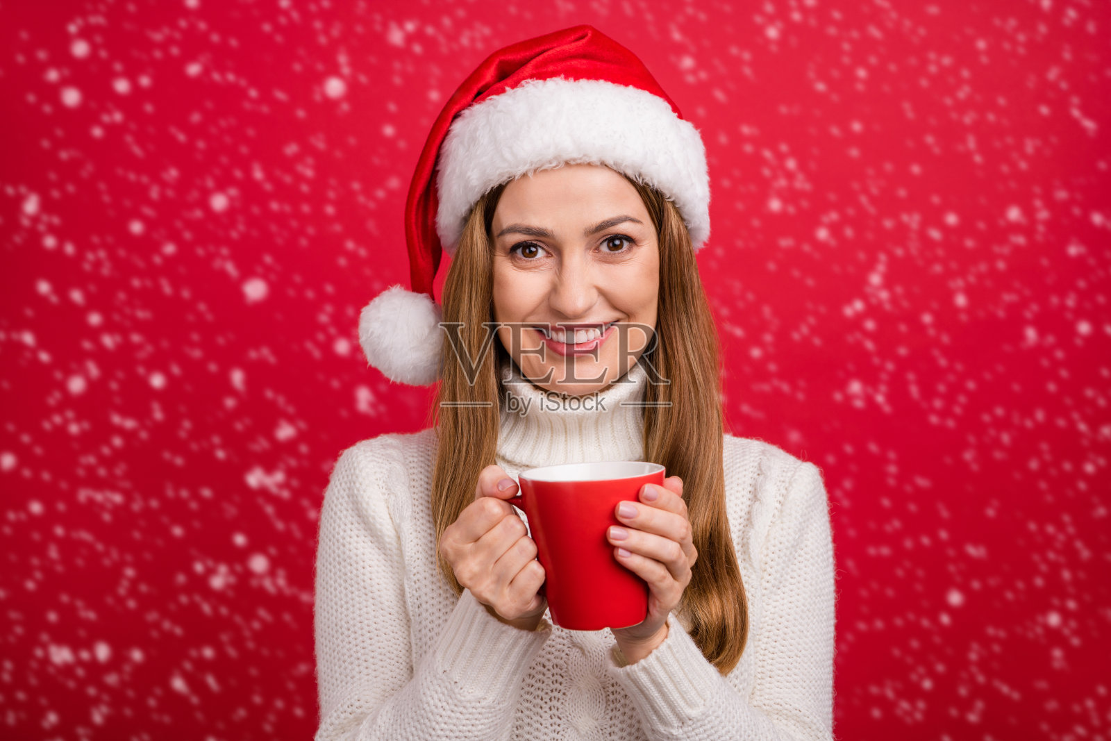 迷人快乐的女性在明亮的红色背景下喝热牛奶，享受节日的休闲时光。照片摄影图片