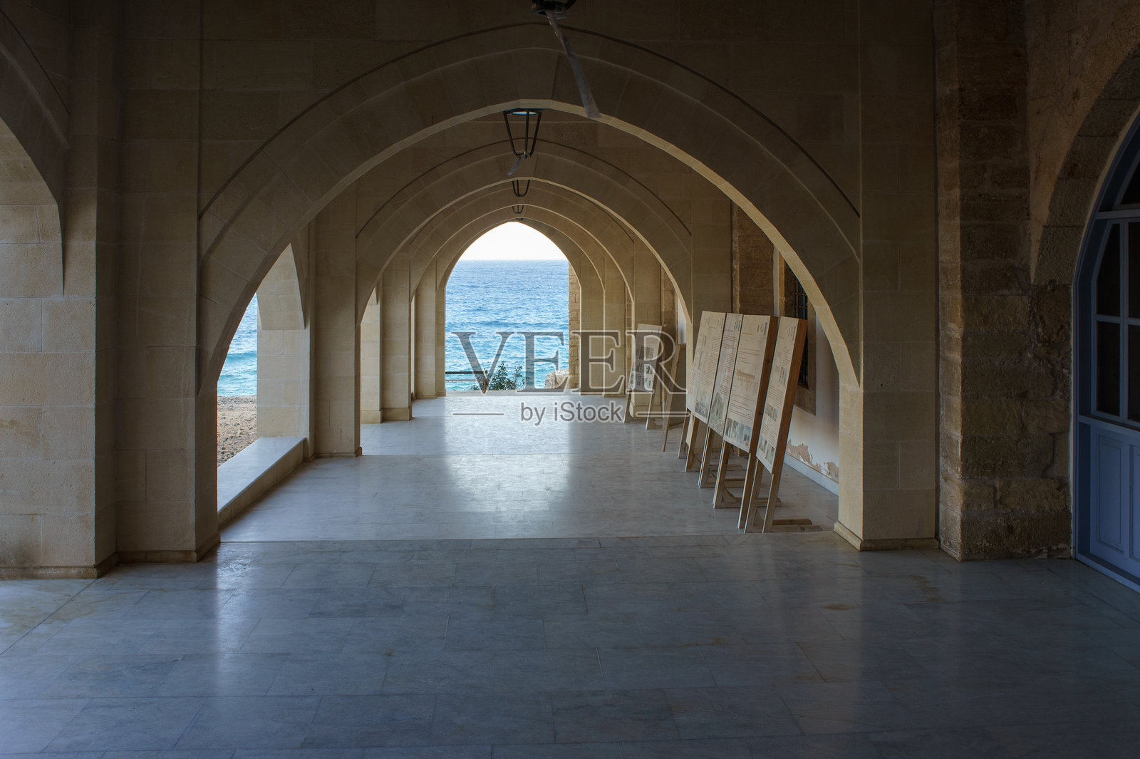 宁静的海滨走廊，拱形天花板俯瞰着正午时分的平静水面。照片摄影图片