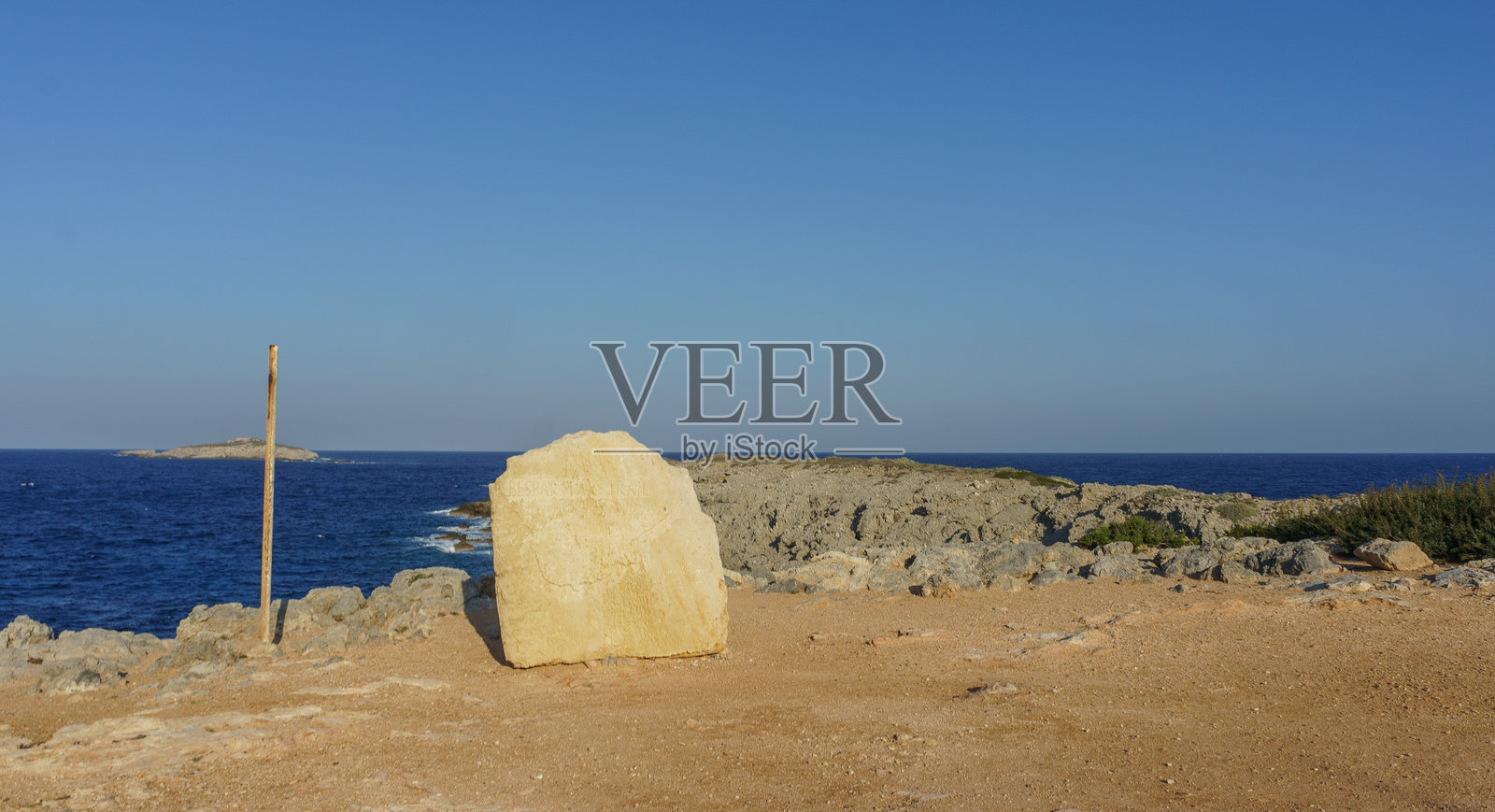 一块孤独的石灰岩在宁静的海岸背景下矗立，天空湛蓝。照片摄影图片