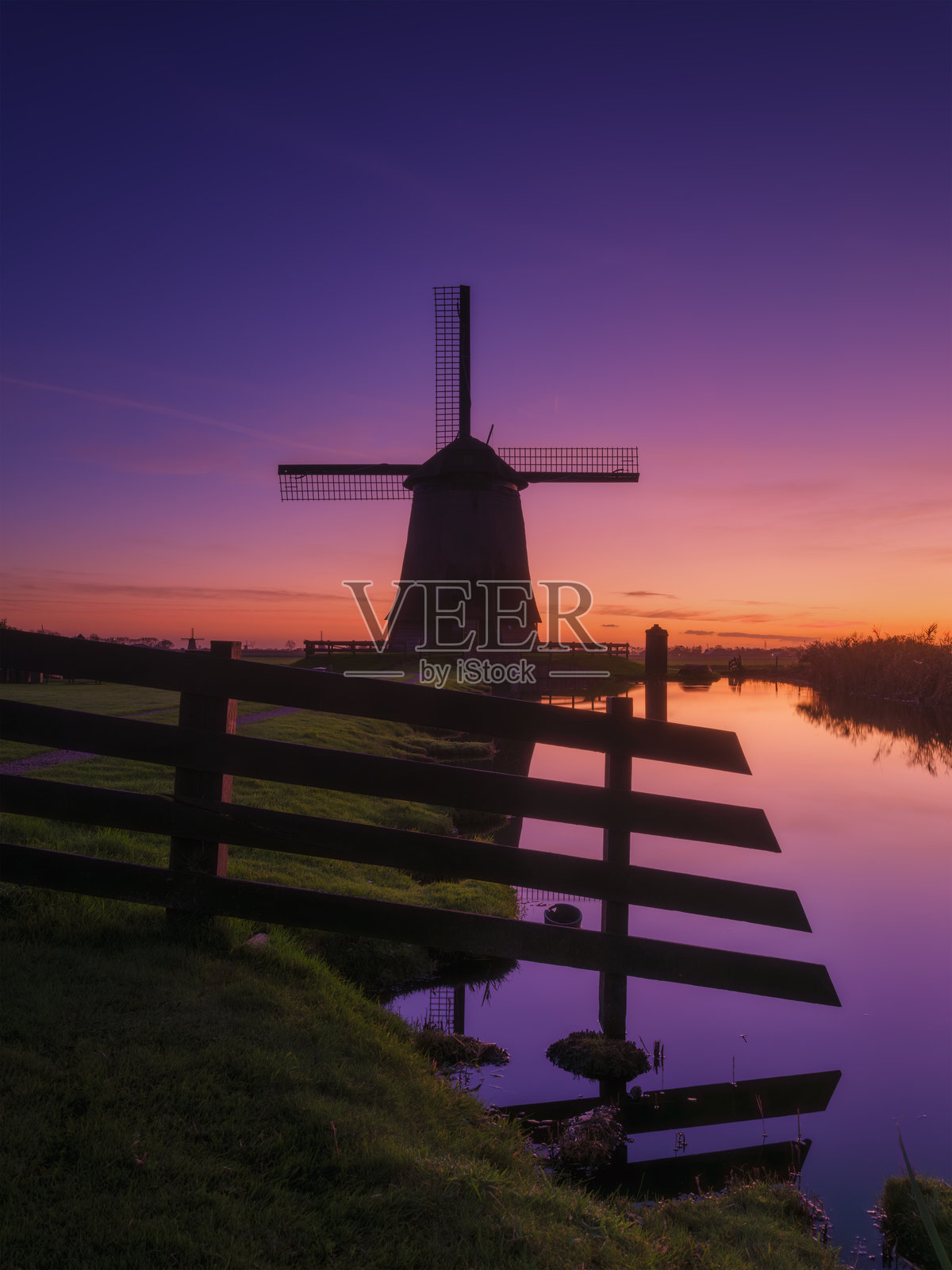 荷兰的风车。荷兰的历史建筑。水面上的倒影。适合明信片、背景和设计的图像。日落时的风景。照片摄影图片