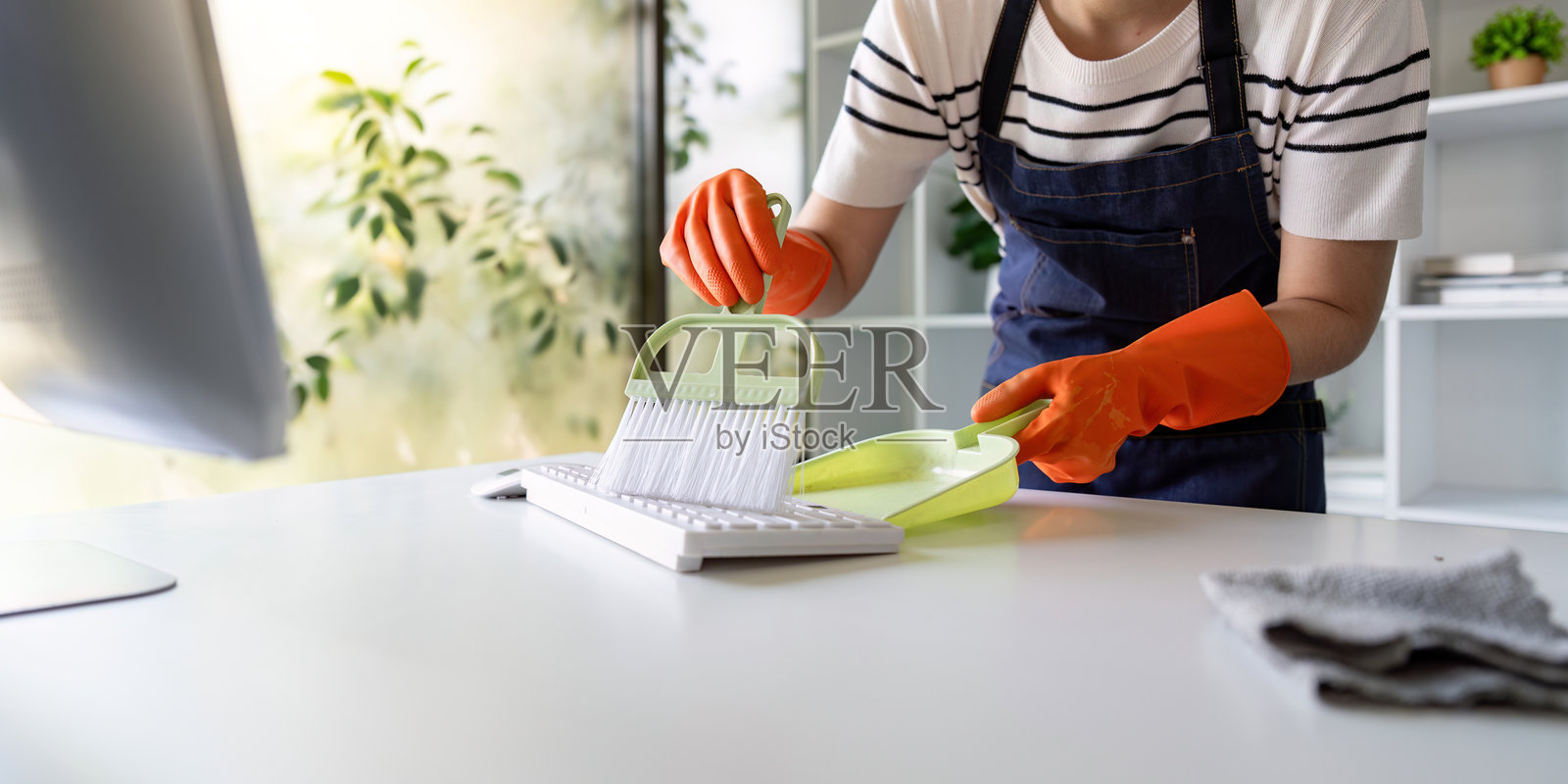 专注的清洁工正在用簸箕清理办公室键盘照片摄影图片