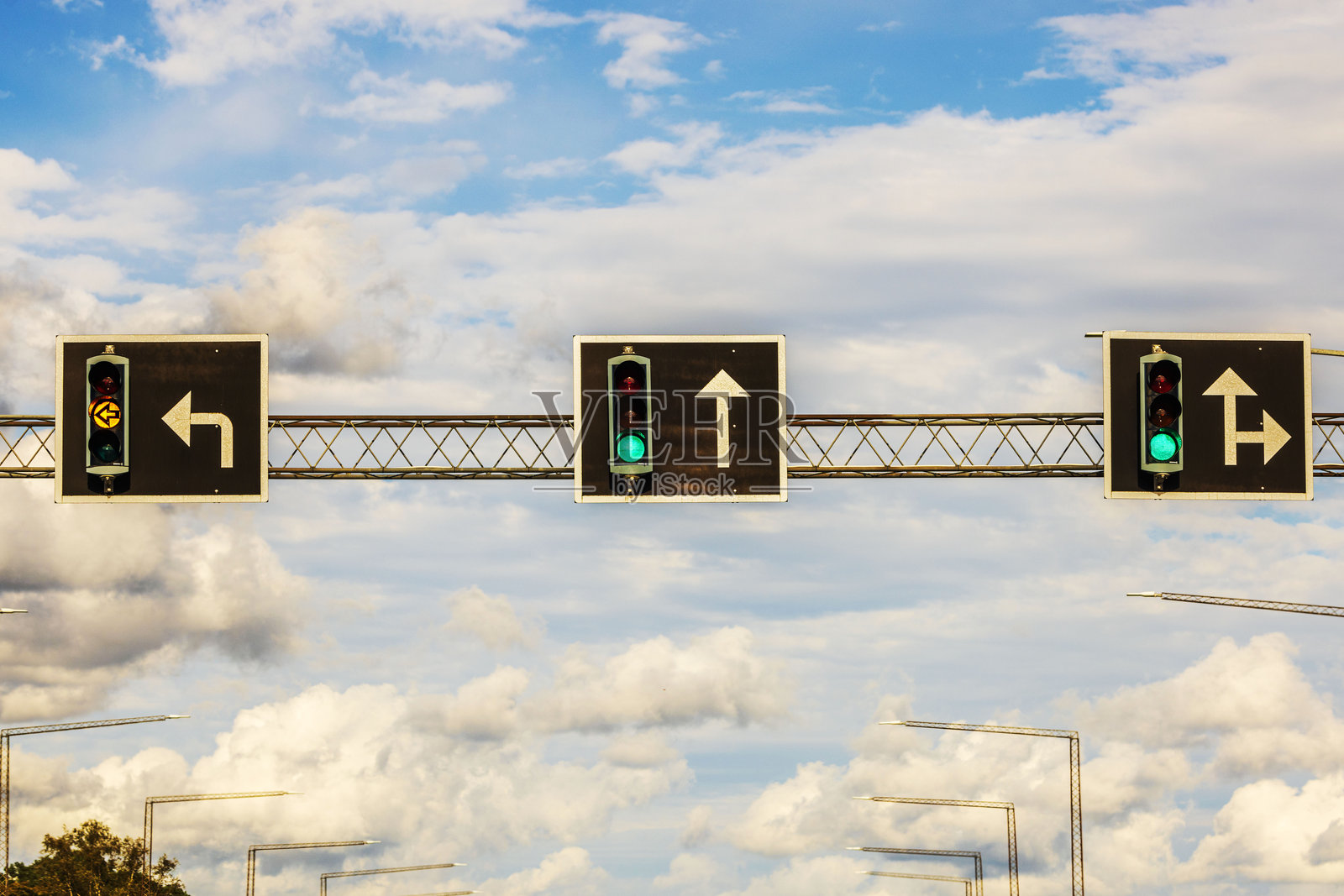 三车道交通信号灯，带有转弯和直行的方向指示标志，背景是阴 cloudy 的天空。瑞典。照片摄影图片