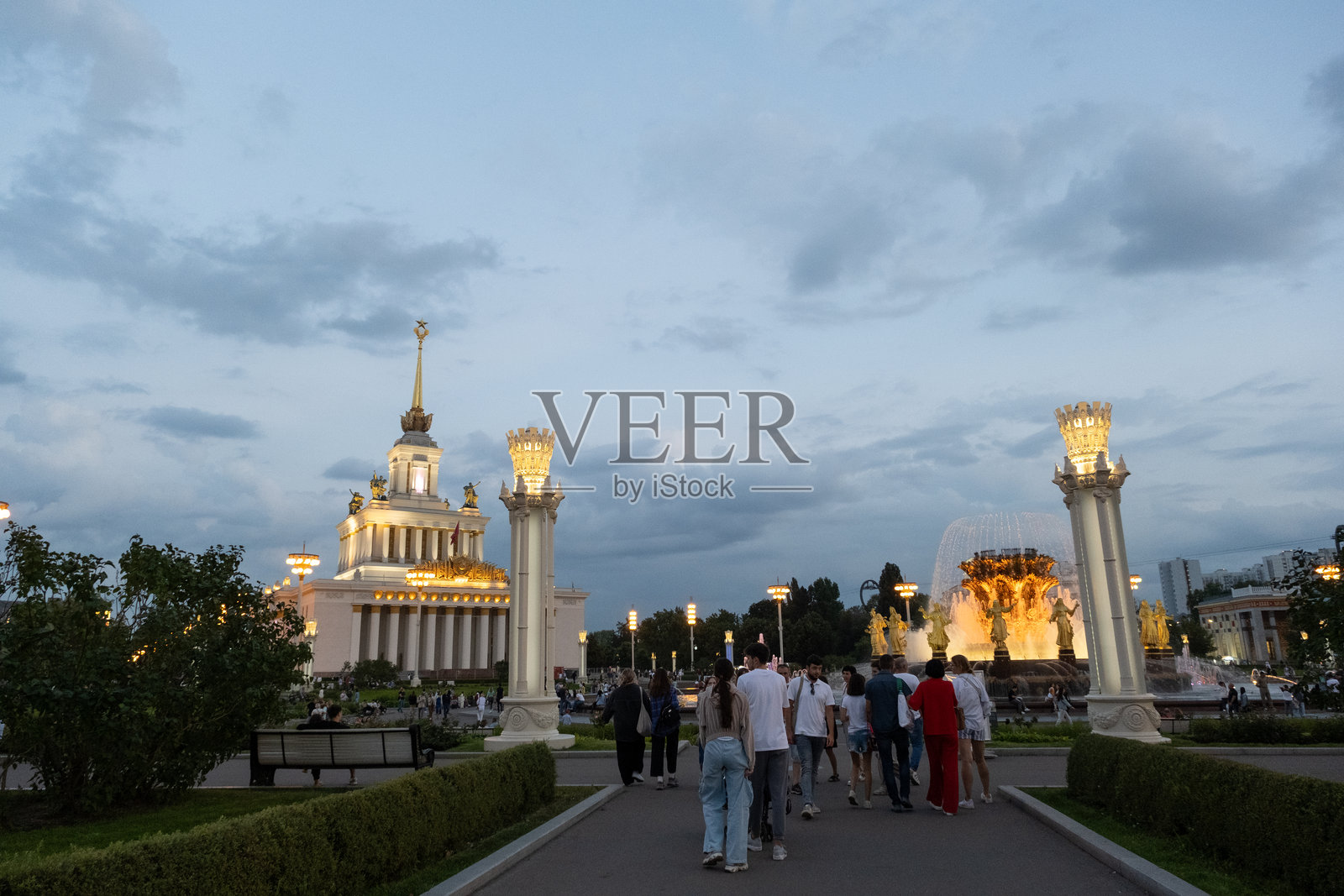 晚间的VDNH展览中心照片，展现了标志性的中央展馆和金色喷泉在柔和灯光下的壮丽景观。照片摄影图片