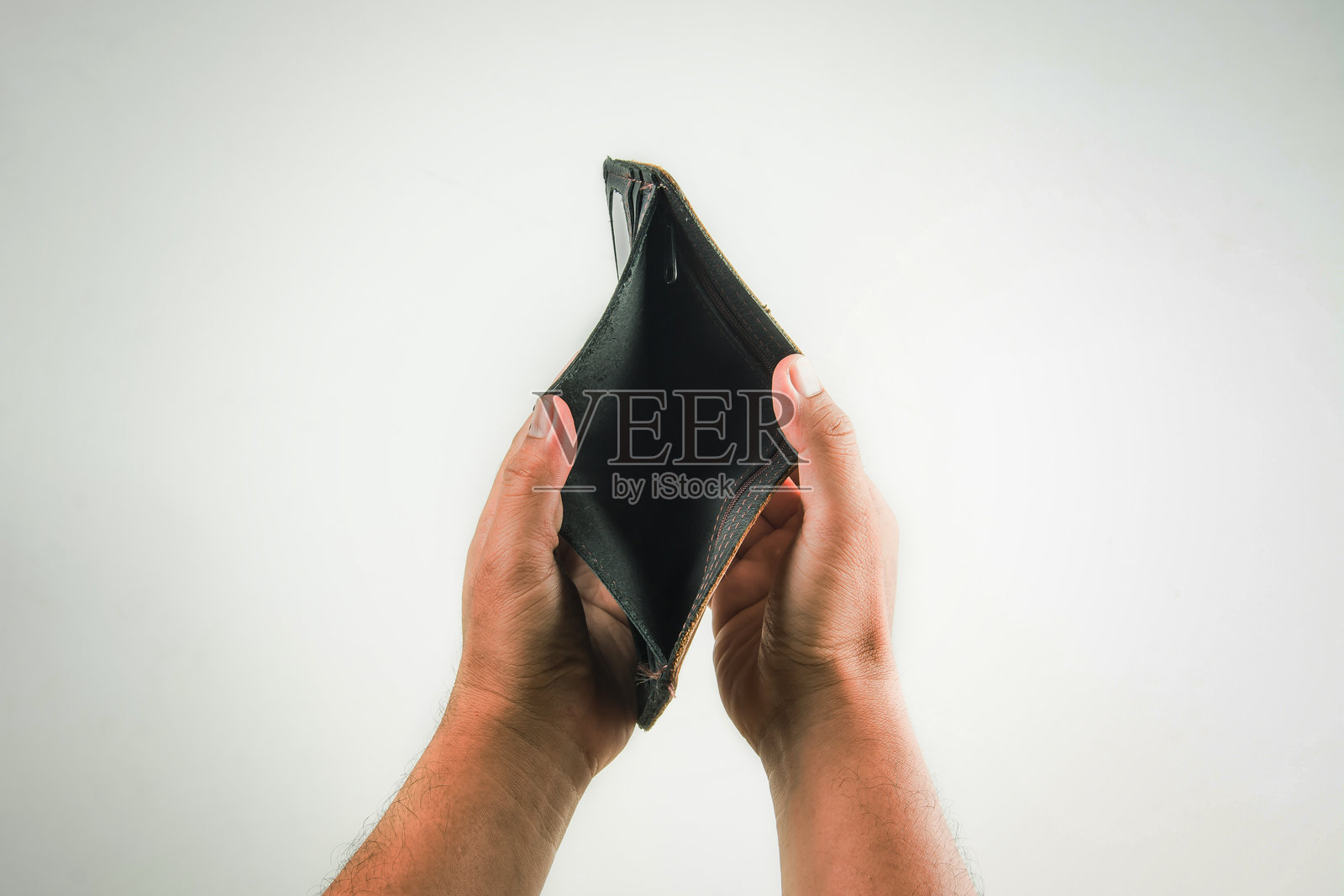 男人手握空钱包，背景为白色。照片摄影图片