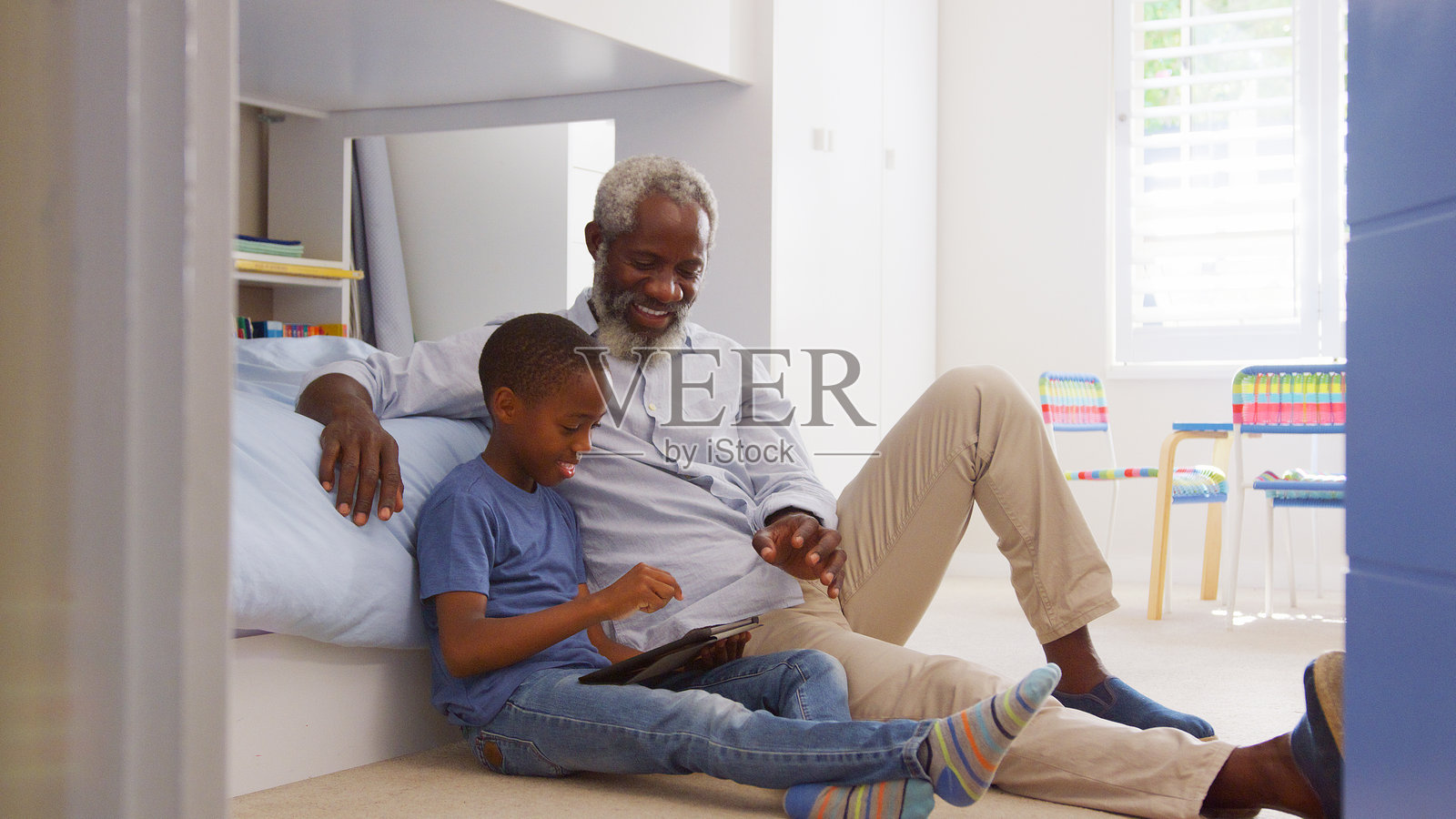 祖父和孙子坐在儿童卧室里一起使用平板电脑照片摄影图片