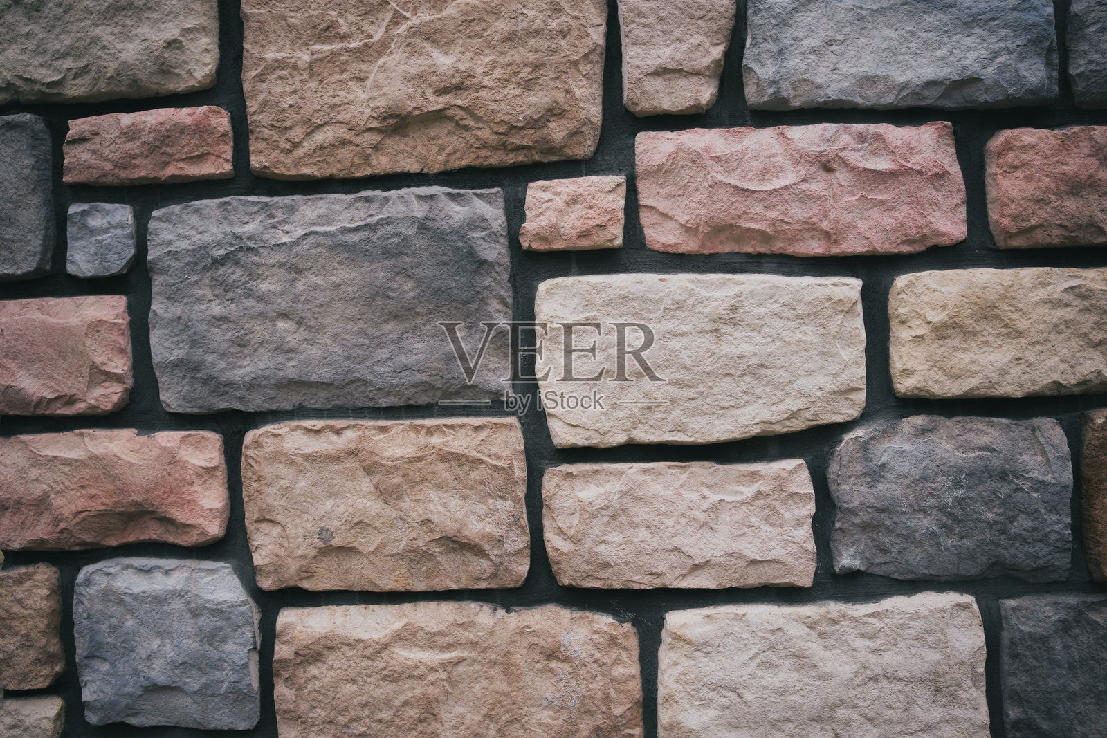 特写镜头展示了一个乡村风格的石墙，砖块呈现出不同深浅的灰色和粉色，适合用作背景或建筑设计。照片摄影图片