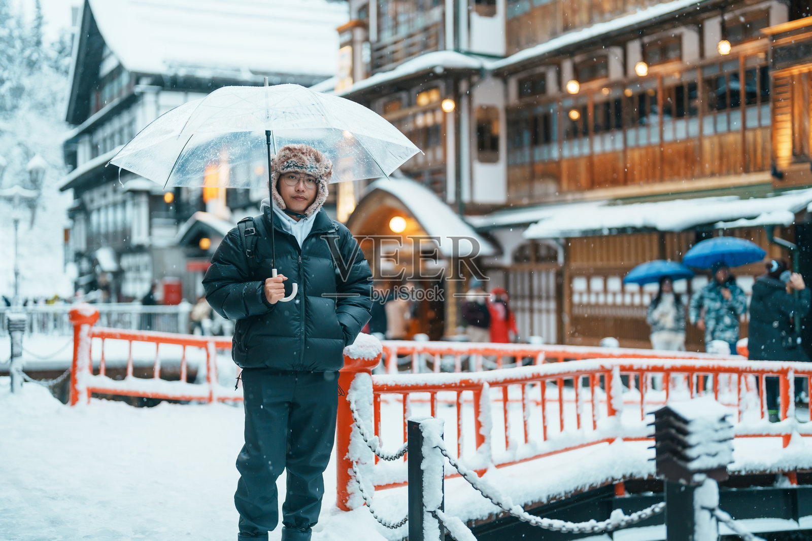男游客在山形的银山温泉游玩，快乐的旅行者在冬季雪景中观光日本温泉村。这是日本著名的旅游景点，适合旅行和度假。照片摄影图片