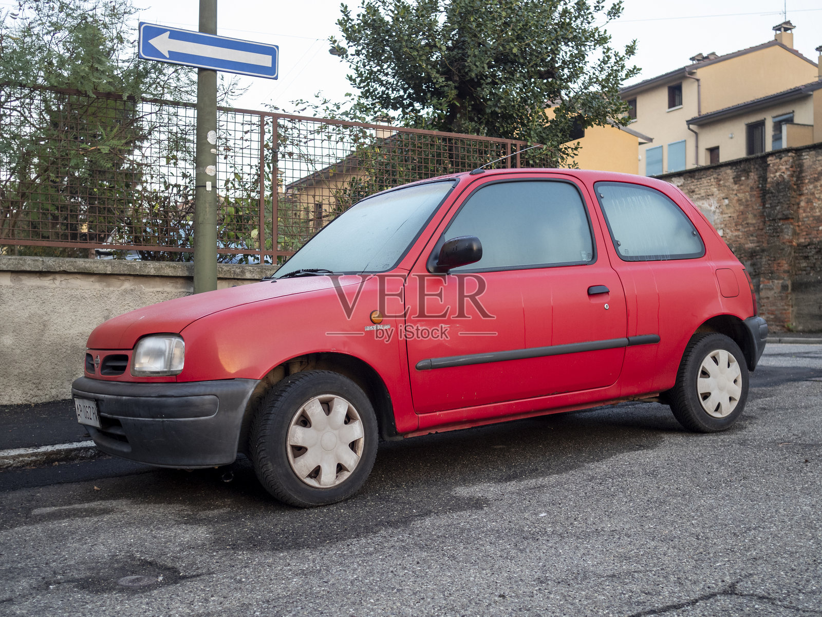 红色日产Micra停在住宅街道上照片摄影图片