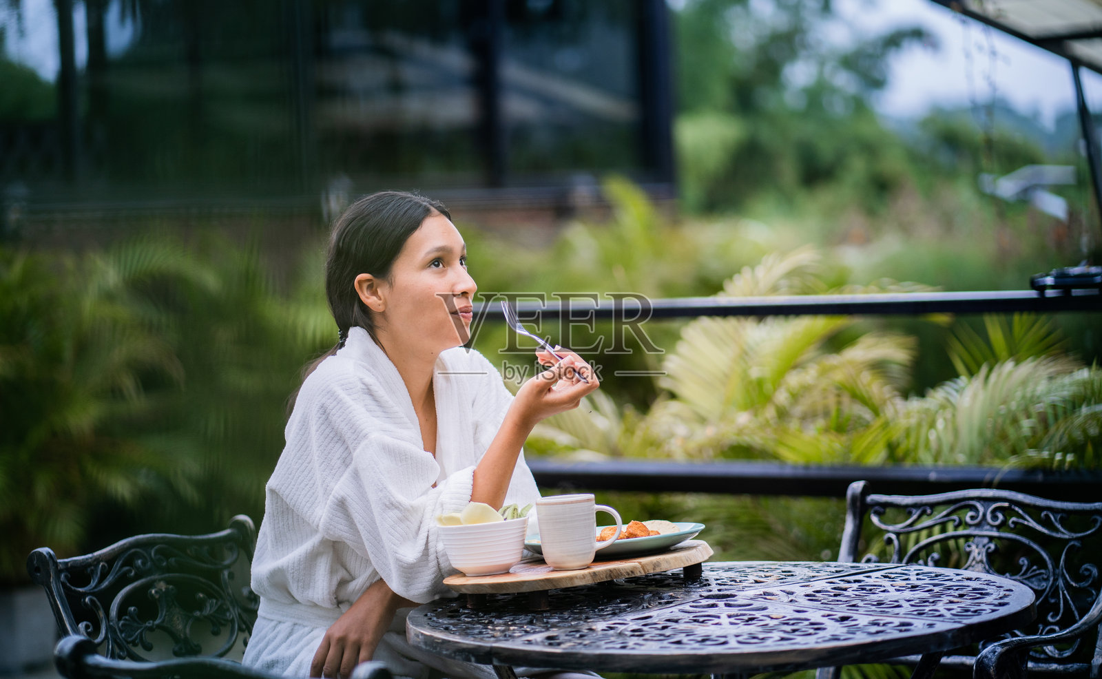 年轻女性坐在户外享受早餐照片摄影图片