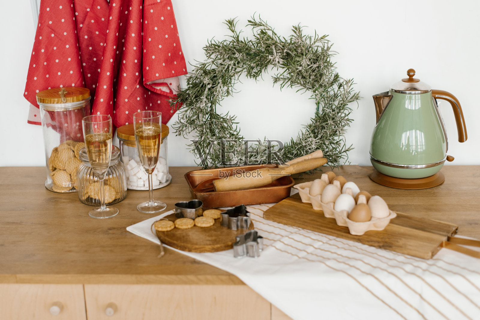 厨房用具。圣诞花环、茶壶、鸡蛋、香槟杯、木质擀面杖放在木制橱柜上。照片摄影图片