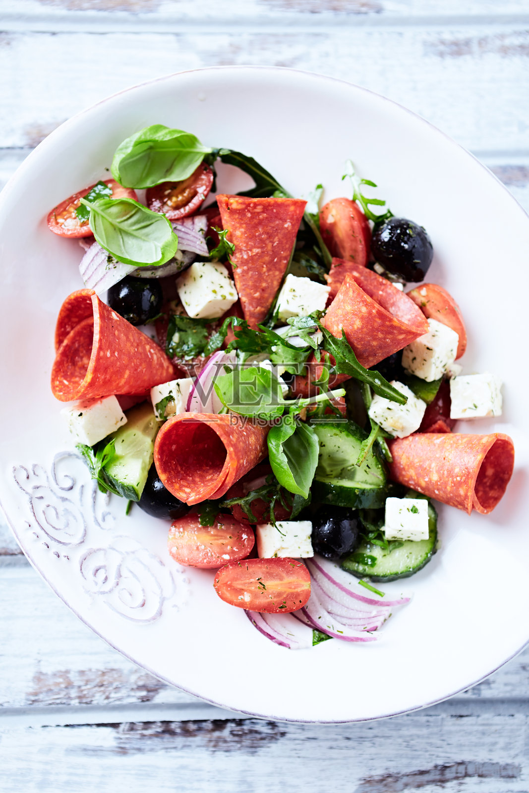 意大利香肠、菲达奶酪、黑橄榄、黄瓜和樱桃番茄的沙拉特写。照片摄影图片