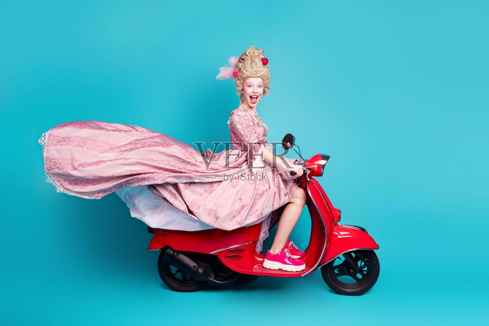 快乐迷人的公主骑着快速摩托车，背景为蓝色。照片摄影图片