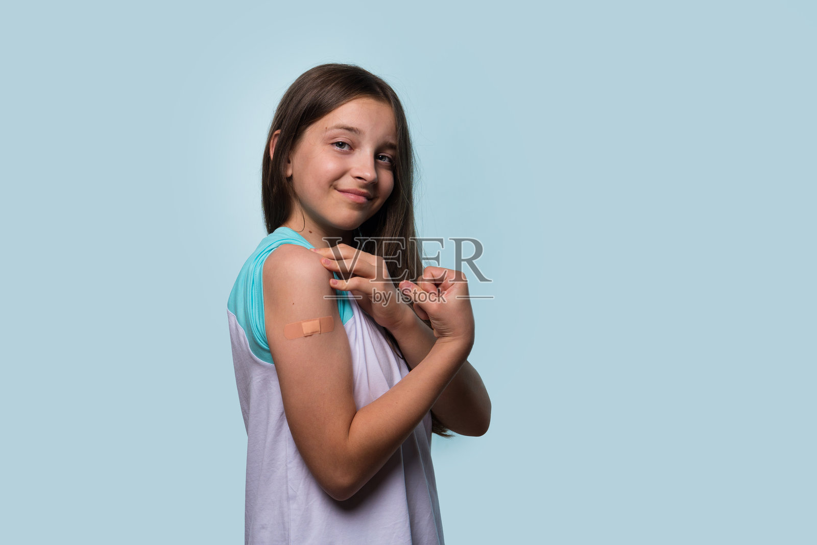 女孩通过弯曲手臂展示她接种疫苗的手臂照片摄影图片