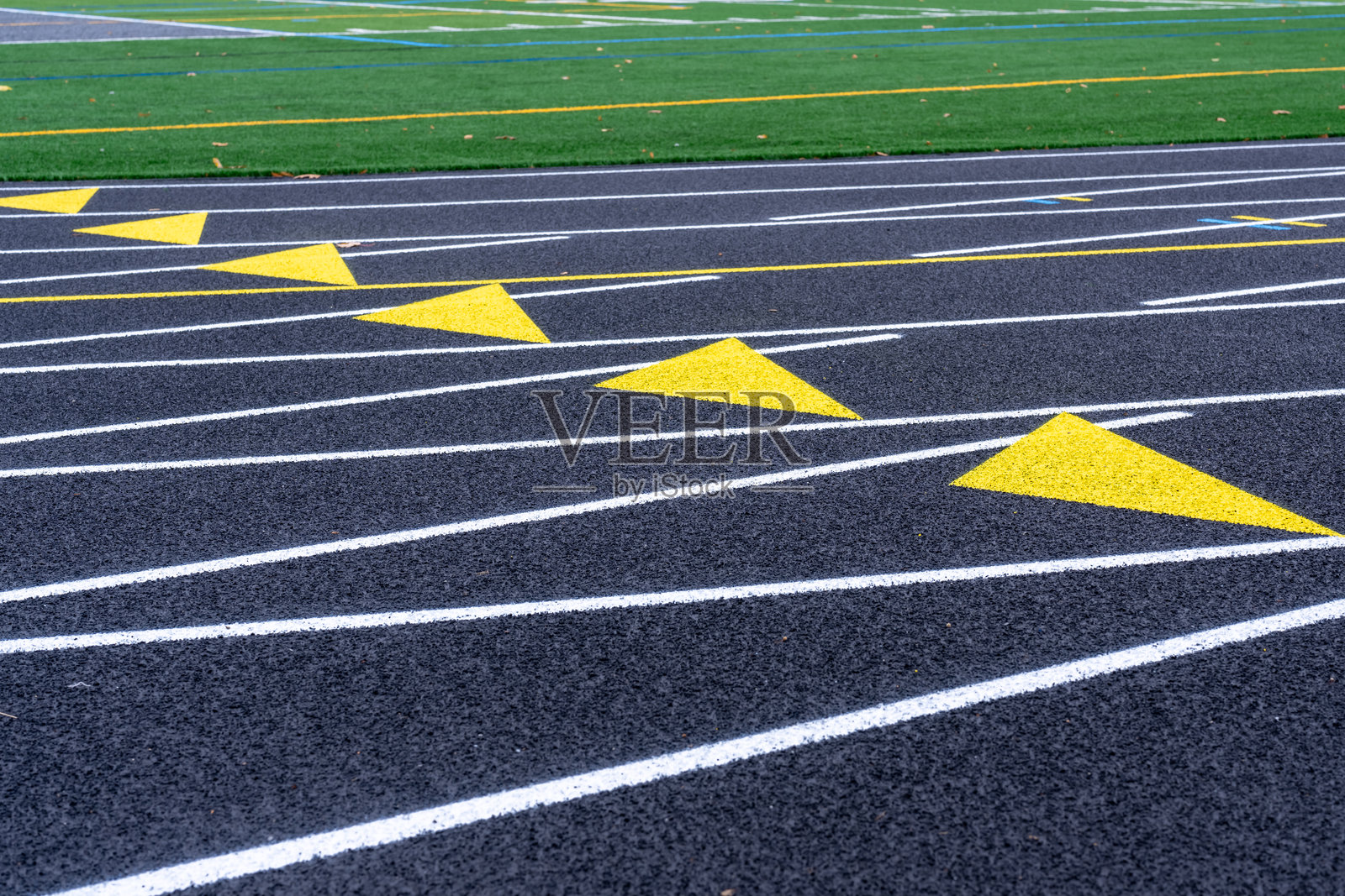 新黑色跑道上黄色交换区标记的特写，配有白色跑道线。照片摄影图片