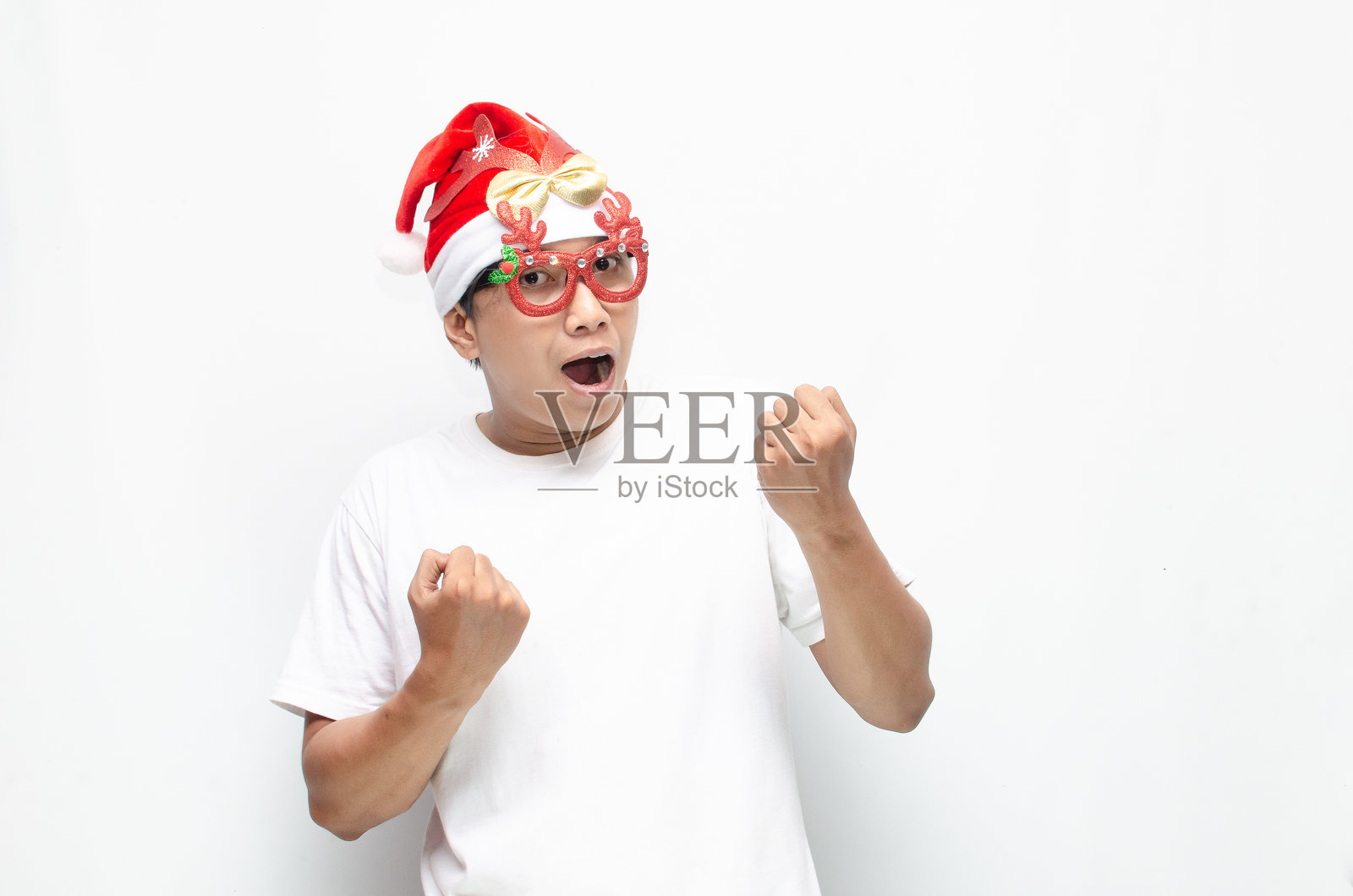 快乐的年轻亚洲男子戴着圣诞老人帽和圣诞眼镜，跳舞庆祝圣诞节。圣诞节和节日概念。照片摄影图片