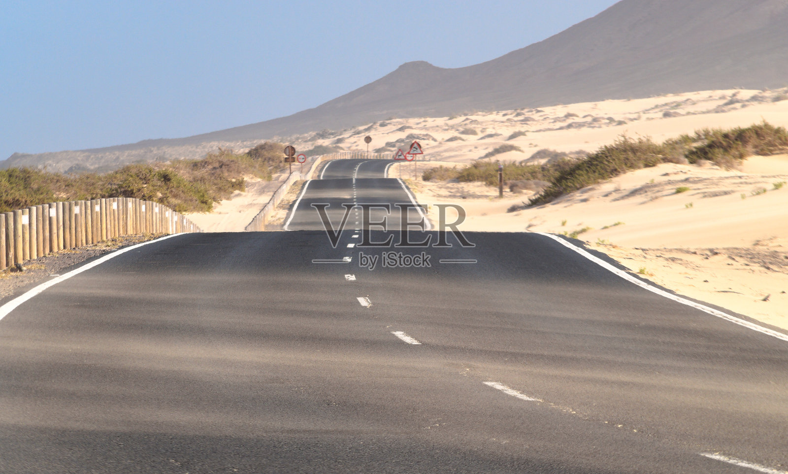 沙子保护围栏与2024年国家地理世界最美海滩的道路平行，位于富埃特文图拉的荒漠岛屿上。全球变暖带来的不确定命运的概念。照片摄影图片